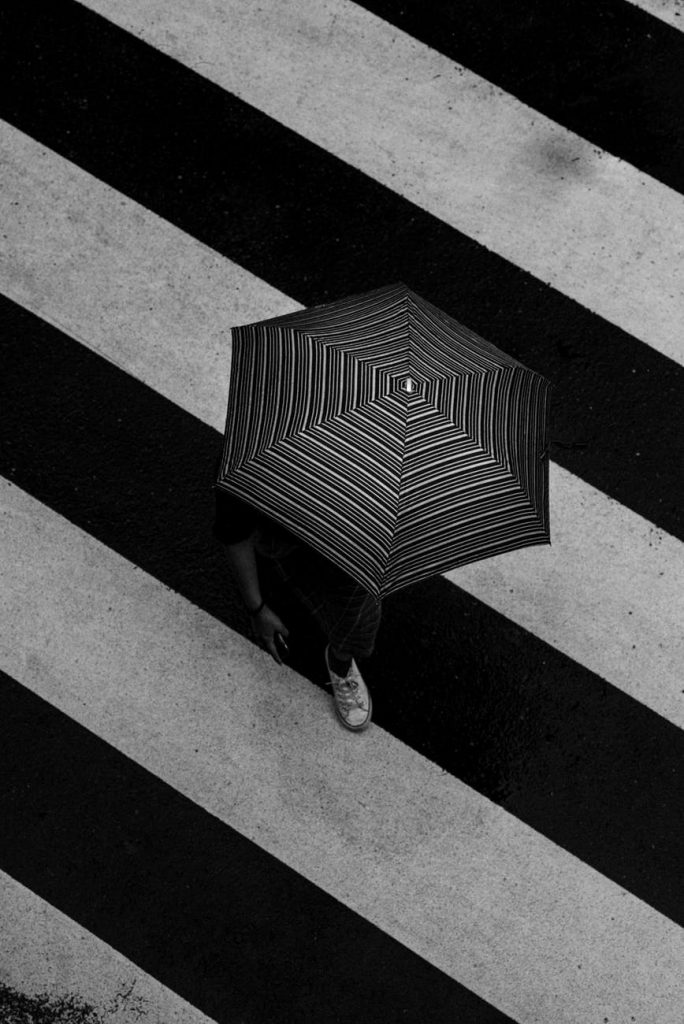 unrecognizable person with umbrella on crosswalk