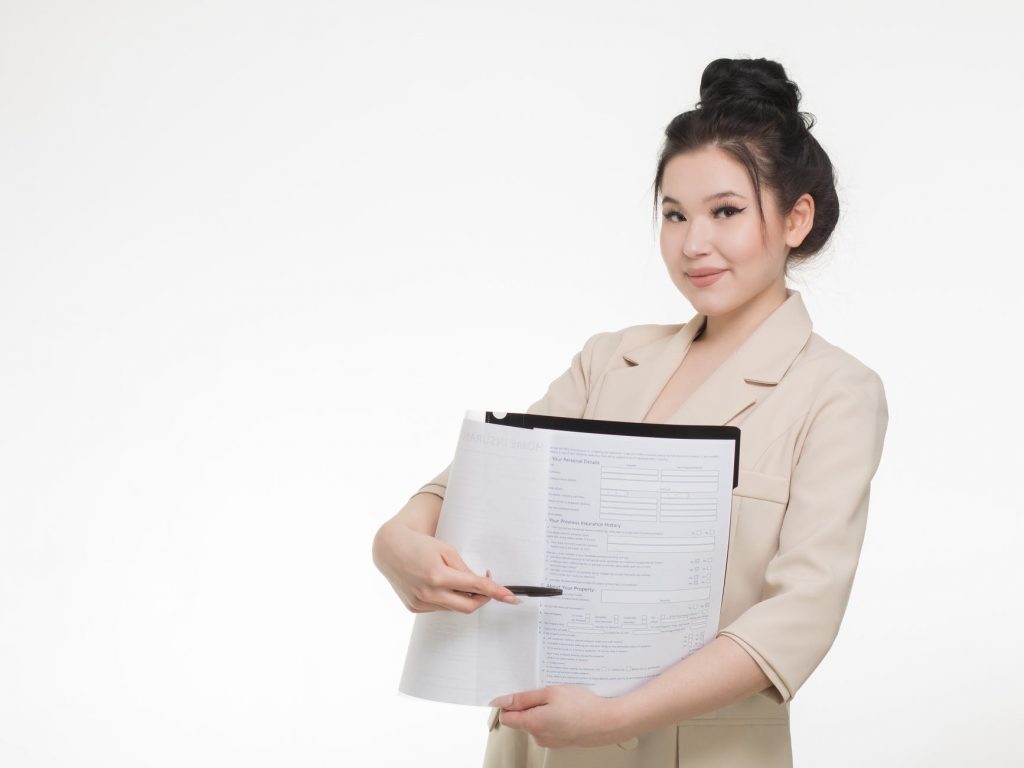 woman in brown blazer holding a pen and file